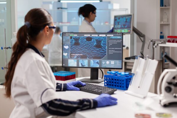 Bioinformática em laboratório com pesquisadora analisando dados biológicos em computador