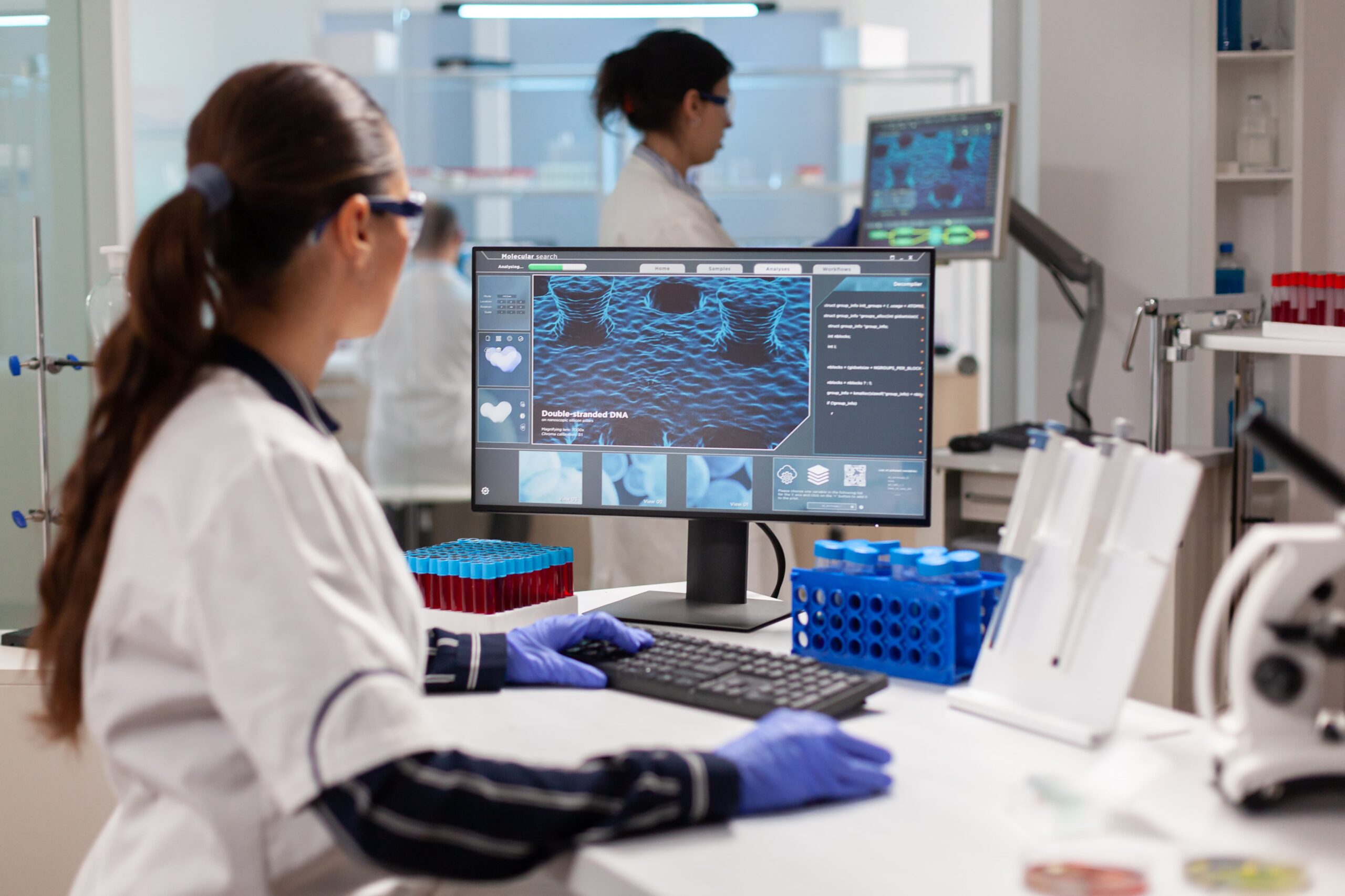 Bioinformática em laboratório com pesquisadora analisando dados biológicos em computador